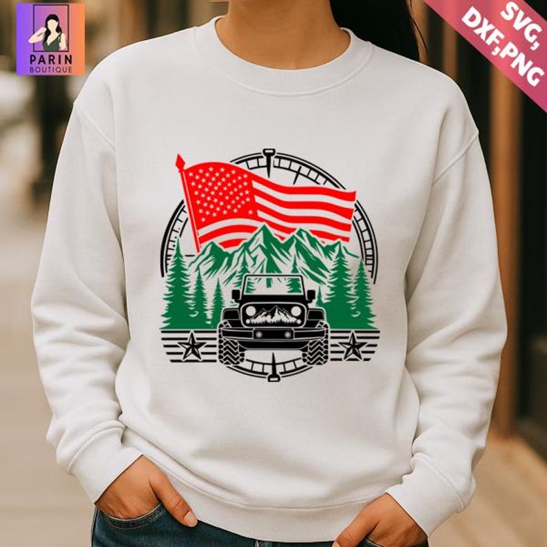 K&ouml;nnte beinhalten: Wei&szlig;es Sweatshirt mit einem grafischen Design. Das Design zeigt eine rot-wei&szlig;-amerikanische Flagge, gr&uuml;ne Berge und einen schwarzen Jeep. Das Design umfasst gr&uuml;ne Kiefern, Sterne und einen kompassartigen Rand.