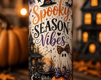 May include: A cylindrical tumbler with a clear lid and metal straw, featuring a graphic print with the text Spooky Season Vibes and Witch's Brew. The design includes a witch hat, a ghost with a leopard print bow, a jack-o'-lantern, and a house.
