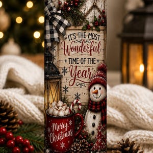 May include: A cylindrical tumbler with a straw featuring a rustic wood background, a snowman, a red mug filled with marshmallows, a lantern, and pine branches. The text reads, It's the most wonderful time of the year and Merry Christmas.
