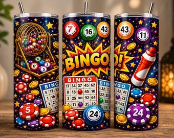 May include: A cylindrical tumbler with a straw featuring a vibrant bingo-themed graphic print. The design includes a gold bingo cage, numbered bingo balls, bingo cards, colorful game chips, and the word BINGO in bold yellow letters on a dark background.