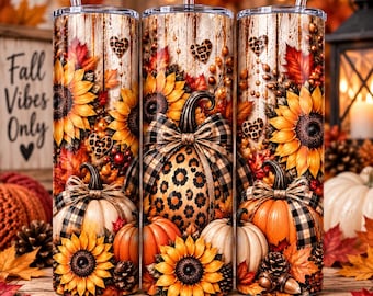 May include: A cylindrical stainless steel tumbler featuring a wrap-around print of sunflowers, pumpkins, and leopard print hearts against a rustic wood background. The design includes a plaid bow on the pumpkins and a clear straw at the top.