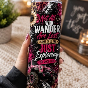 May include: A cylindrical stainless steel tumbler with a metal straw, featuring a black and pink leopard print background, a sunflower, and a pink off-road vehicle. The text reads: Not All Who Wander Are Lost, SOME OF US ARE JUST EXPLORING THE GOOD LIFE.