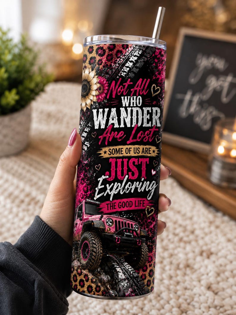 May include: A cylindrical stainless steel tumbler with a metal straw, featuring a black and pink leopard print background, a sunflower, and a pink off-road vehicle. The text reads: Not All Who Wander Are Lost, SOME OF US ARE JUST EXPLORING THE GOOD LIFE.