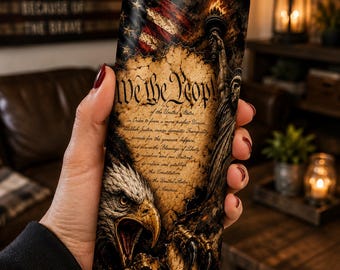 May include: A cylindrical tumbler with a clear lid and metal straw, featuring a graphic print of the United States Constitution text, the Statue of Liberty holding a torch, an American flag, and a bald eagle with its beak open and talons extended.