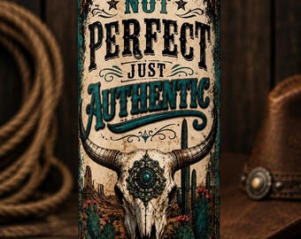 May include: A cylindrical tumbler with a metal straw featuring a desert landscape graphic, a steer skull with a turquoise-colored medallion, and the text NOT PERFECT JUST AUTHENTIC. The design includes cacti, a leopard print base, and ornate borders.