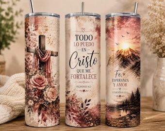 May include: Three cylindrical tumblers with metal straws featuring religious themes. One shows a wooden cross with roses, another displays the text "TODO LO PUEDO EN CRISTO QUE ME FORTALECE FILIPENSES 4:13", and the third depicts a mountain sunset with "Fe, ESPERANZA Y AMOR 1 CORINTIOS 13:13".