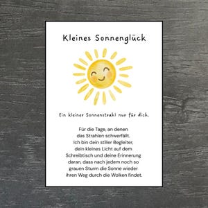 Può includere: Un cartoncino rettangolare bianco con un'illustrazione ad acquerello di un sole giallo con un volto sorridente. Il testo recita: Kleines Sonnenglück, Ein kleiner Sonnenstrahl nur für dich. Für die Tage, an denen das Strahlen schwerfällt. Ich bin dein stiller Begleiter.