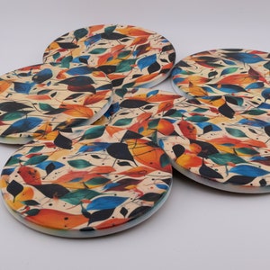 May include: Set of six round coasters with a colourful abstract design featuring leaves in shades of orange, red, blue, green, and black on a cream background.