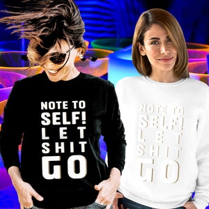 Zwei Frauen auf einer Party im Sweatshirt. Einmal schwarz und einmal weiß. Auf den Shirts steht in sehr großen Buchstaben über das ganze Shirt der Spruch: Not to self! Let Shit go!