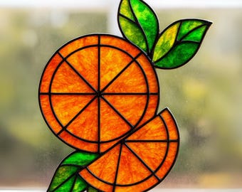 May include: A stained glass orange slice design with a black outline. The orange fruit is a vibrant orange color, with green and yellow leaves. The design is likely a window cling or suncatcher.