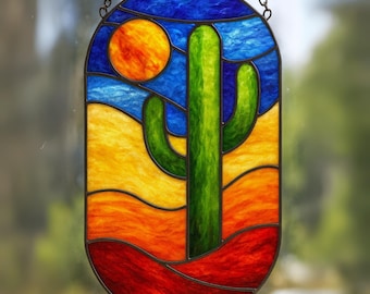 May include: Stained glass panel depicting a desert scene with a green cactus, a yellow sun, and a blue sky. The panel is framed in black and hangs from a chain. The desert landscape features shades of red, orange, and yellow.
