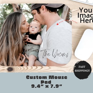May include: A custom mouse pad featuring a photo of a family of three. The photo shows a man, a woman, and a baby. The man is kissing the baby on the head. The woman is smiling and looking at the camera. The text "The Yocoms" is written on the mouse pad.