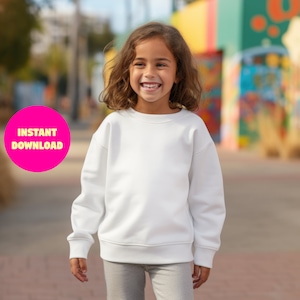 May include: A young person wearing a white sweatshirt with long sleeves and grey leggings. The person is standing in front of a colorful background.