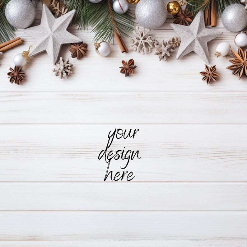 Pu&ograve; includere: Vista dall'alto di una superficie in legno bianco decorata con ornamenti natalizi. Palline argentate e dorate, decorazioni a forma di stella, bastoncini di cannella e rami di pino sono disposti in alto. Il testo "your design here" &egrave; scritto in corsivo.
