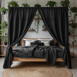 Puede incluir: Una moderna configuración de dormitorio con una cama de madera, ropa de cama gris oscuro y una manta a juego. Cortinas negras cubren la cama, creando un efecto de dosel. Una alfombra redonda de yute está en el suelo, y plantas colgantes añaden un toque natural.
