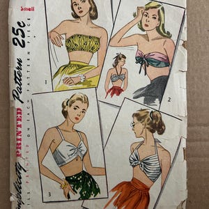Könnte beinhalten: Vintage Simplicity Schnittmuster 2026 für Größe Small. Das Cover zeigt Illustrationen verschiedener zweiteiliger Badeanzug-Designs. Das Muster ist gedruckt, mit Details auf jedem Stück. Das Cover weist Gebrauchsspuren auf.
