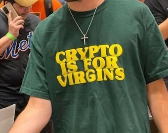 Puede incluir: Una persona lleva una camiseta verde con el texto "CRYPTO IS FOR VIRGINS" en letras amarillas. La persona lleva una cadena de plata con un colgante de cruz.