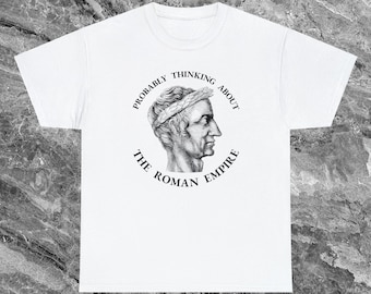 以下が含まれることがあります： 白いTシャツ。ローレルリースをつけたローマの胸像の白黒イラストが描かれています。画像周りのテキストは「Probably Thinking About The Roman Empire」と書かれています。