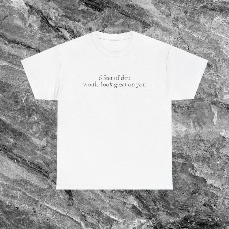 May include: White t-shirt with the text "6 feet of dirt would look great on you" in a simple, sans-serif font. The shirt has a crew neck and short sleeves. The text is centered on the front of the shirt.