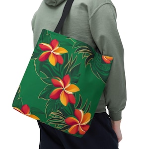 May include: A green tote bag featuring a vibrant floral pattern with red, yellow, and orange flowers and green leaves. The bag has a black strap and is carried over the shoulder.