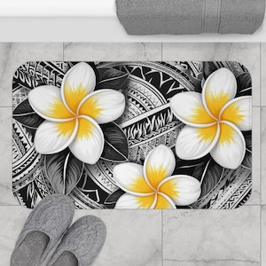 May include: Black and white bath mat with a Polynesian tribal design and white plumeria flowers with yellow centers.