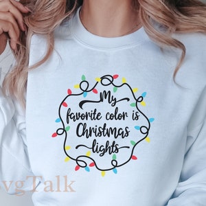 May include: A light blue sweatshirt with the text "My favourite colour is Christmas lights" in black lettering surrounded by a circle of colourful Christmas lights.