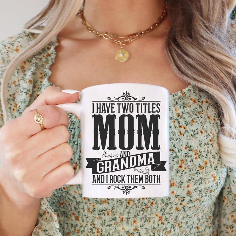 Puede incluir: Taza de cer&aacute;mica blanca con texto negro que dice "Tengo dos t&iacute;tulos Mam&aacute; y Abuela y los rockeo ambos".