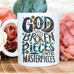 May include: White ceramic coffee mug with a gold and teal design. The mug features the text "God turns broken pieces into masterpieces".