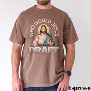Puede incluir: Una camiseta marr&oacute;n con un gr&aacute;fico de Jes&uacute;s sosteniendo un bal&oacute;n de f&uacute;tbol. El texto "Who Would Jesus Draft" est&aacute; impreso en la camiseta.