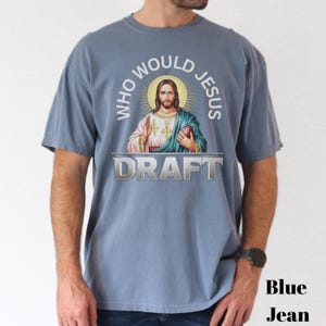 Puede incluir: Una camiseta azul con un gr&aacute;fico de Jes&uacute;s sosteniendo un bal&oacute;n de f&uacute;tbol y el texto "Who Would Jesus Draft".