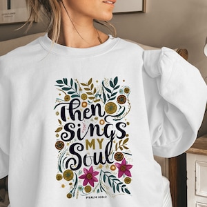 May include: White sweatshirt with a floral design and the text "Then Sings My Soul" with the scripture reference "Psalm 108:2".