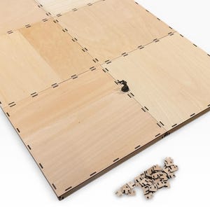 Op de afbeelding: Een lichtgekleurd houten spelbord met een rasterpatroon, met een klein beeldje en een verzameling puzzelstukjes. Het bord is opgebouwd uit meerdere rechthoekige panelen. De puzzelstukjes zijn lichtgekleurd en hebben een unieke vorm.