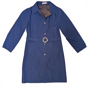 May include: A navy blue trench coat with a matching belt and a large buckle. The coat has a collared neckline, long sleeves, and a button-down front. The interior lining is brown.