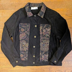 May include: A white ceramic mug with a black handle and the text "But First, Coffee" in a black, handwritten-style font. The mug is on a white surface.