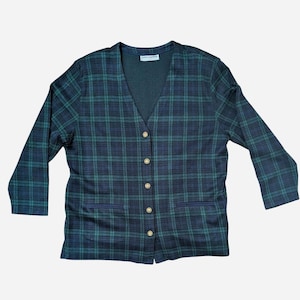 May include: A dark green and navy blue plaid blazer with a V-neck and long sleeves. The blazer has gold-colored buttons and two front pockets. The garment is made of a soft material.