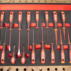 Peut inclure: Un ensemble de 16 tournevis dans un plateau en mousse noire. Les tournevis ont des manches rouges et noirs avec le nom de la marque "Milwaukee" imprimé dessus. Les tournevis sont disposés en deux rangées de huit.