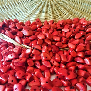 Peut inclure: Un grand tas de perles rouges de forme triangulaire. Les perles sont faites d'un matériau lisse et poli et ont un trou au centre.