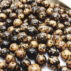 Peut inclure: Gros plan sur un tas de perles rondes de couleur marron et noir. Les perles sont lisses et polies.