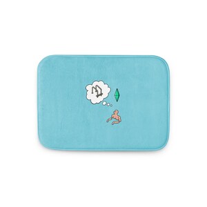 May include: A light blue rectangular bath mat with rounded corners. The mat features a cartoon illustration of a person, a thought bubble with a ladder, and a green diamond. The design is in white, green, and brown.