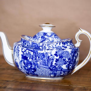 Könnte beinhalten: Eine blaue und weiße Porzellan-Teekanne mit floralem Muster und goldenen Akzenten. Die Teekanne hat einen Deckel und einen Henkel.