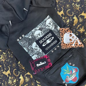 Könnte beinhalten: Schwarzer Hoodie mit verschiedenen aufgenähten Patches. Die Patches beinhalten ein Totenkopf- und Rosenmotiv, einen Patch mit dem Text "Siouxsie and the Banshees", einen Leopardenfell-Patch mit einem Totenkopf, einen roten Patch mit dem Text "The Damned" und einen blauen Patch mit einem Vogel und dem Text "Forever Love".