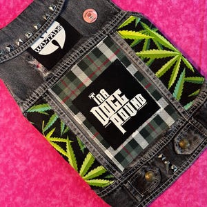 May include: A black denim vest with various patches, including a green marijuana leaf design, a plaid patch with the text "The Doge Pound", and a black and white Wu-Tang Clan logo patch.