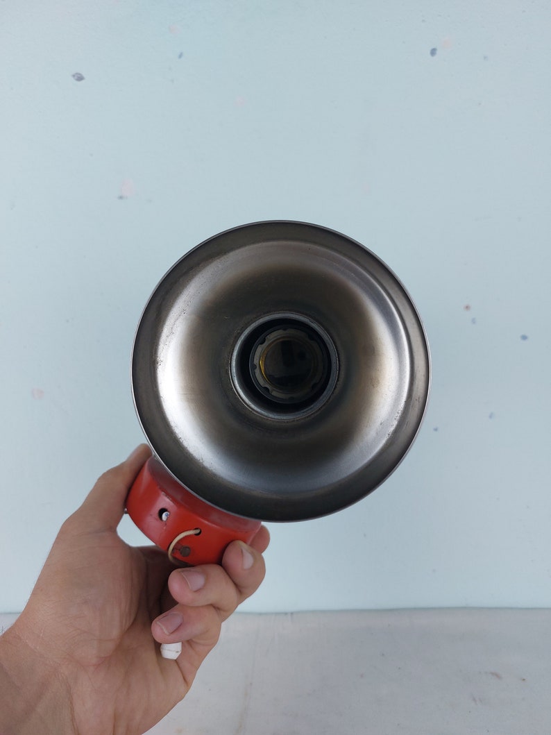 May include: A vintage metal lampshade with a red base and a silver reflector. The lampshade has a simple design and is perfect for adding a touch of retro style to any room.