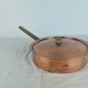 May include: A copper saucepan with a brass handle and lid. The lid has a brass knob.