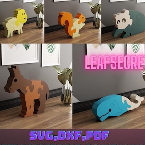 May include: Five wooden puzzle toys in the shapes of a sheep, rabbit, bear, donkey, and whale. The puzzles are made of interlocking pieces and are painted in bright colors. The puzzles are arranged on a wooden surface. The text "LEAFSECRET" is visible in the background.