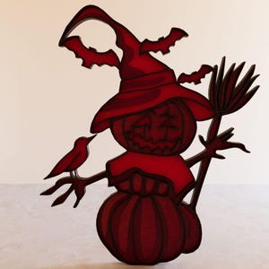 May include: A red wooden Halloween decoration of a pumpkin with a witch's hat, holding a broom and a small bird.
