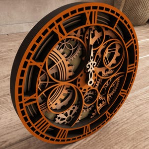 May include: A layered wooden clock with an intricate gear design. The clock features Roman numerals and a black and orange color scheme. The clock hands are a light beige color. The clock is a decorative item.