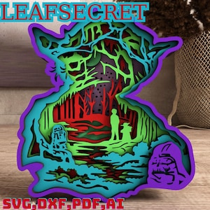 Könnte beinhalten: Ein mehrschichtiges Papierbastel-Design mit einer grünen Yoda-Figur vor einer Waldszene. Die Szene umfasst einen roten und grünen Wald, einen blauen Fluss und eine lila Darth Vader-Figur in der unteren rechten Ecke. Das Design ist oben mit "LEAFSECRET" und unten mit "SVG, DXF, PDF, AI" beschriftet.