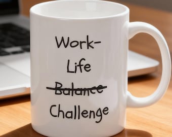 May include: White ceramic mug with the words "Work-Life Challenge" in black lettering. The word "Balance" is crossed out. The mug sits on a wooden desk next to a laptop, a notebook, and a small potted plant.