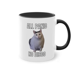 Könnte beinhalten: Weiße Keramik-Kaffeetasse mit schwarzem Rand und Henkel. Die Tasse zeigt ein Schwarzweißbild einer Katze mit dem Text "ALL PANIC NO DISCO" auf der Vorderseite.